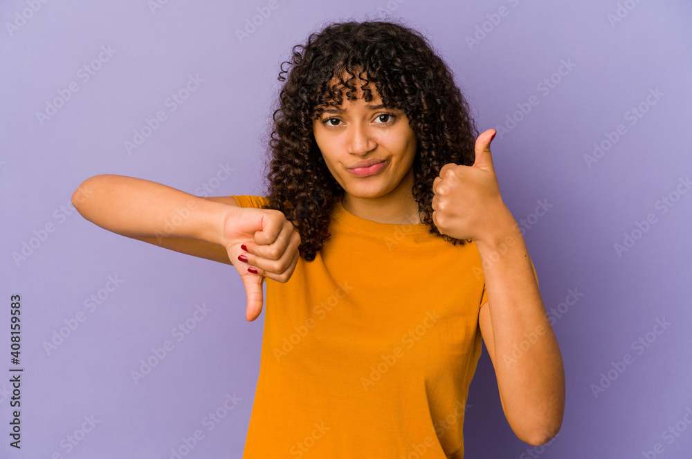 Young african american afro woman isolated showing thumbs up and thumbs down, difficult choose concept Young african american afro woman isolated showing thumbs up and thumbs down, difficult choose concept