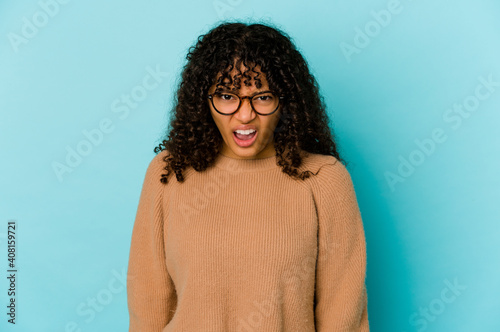 Young african american afro woman isolated shouting very angry, rage concept, frustrated. © Asier