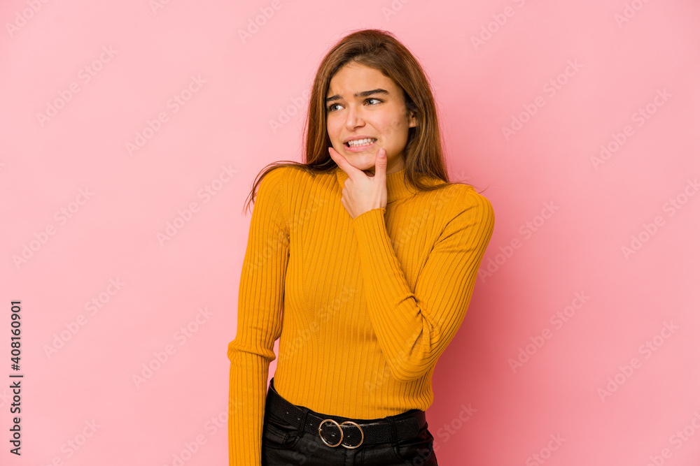 Young skinny caucasian teenager girl touching back of head, thinking and making a choice.