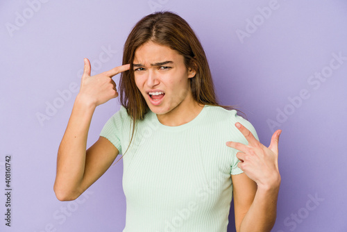 Young skinny caucasian girl teenager on purple background showing a disappointment gesture with forefinger.