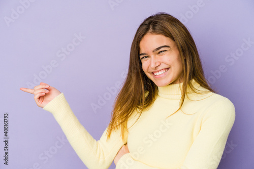 Young skinny caucasian girl teenager on purple background smiling cheerfully pointing with forefinger away.