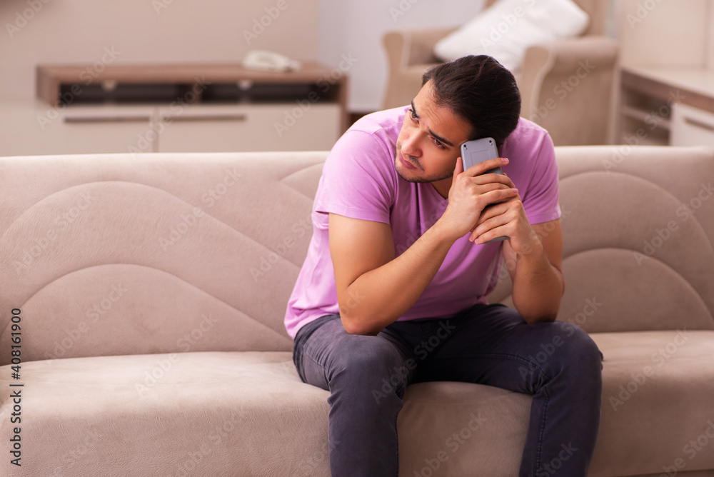 Fototapeta premium Young man watching tv at home during pandemic