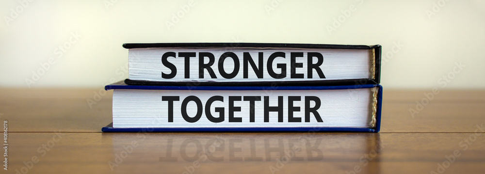 Stronger together symbol. Concept words 'stronger together' on books on a beautiful wooden table, white background. Business, motivational and stronger together concept.
