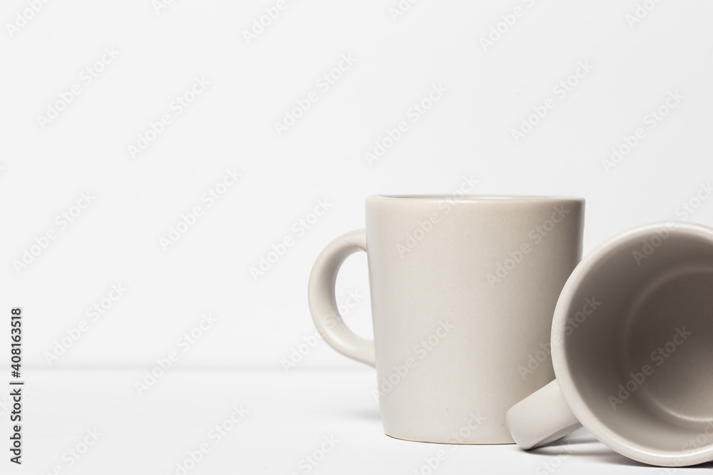 Two white ceramic espresso mugs against a white background coffee house cafe art. Two white ceramic espresso mugs against a white background coffee house cafe art.