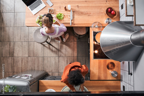 Girl standing at the table while cooking with her bestie photo