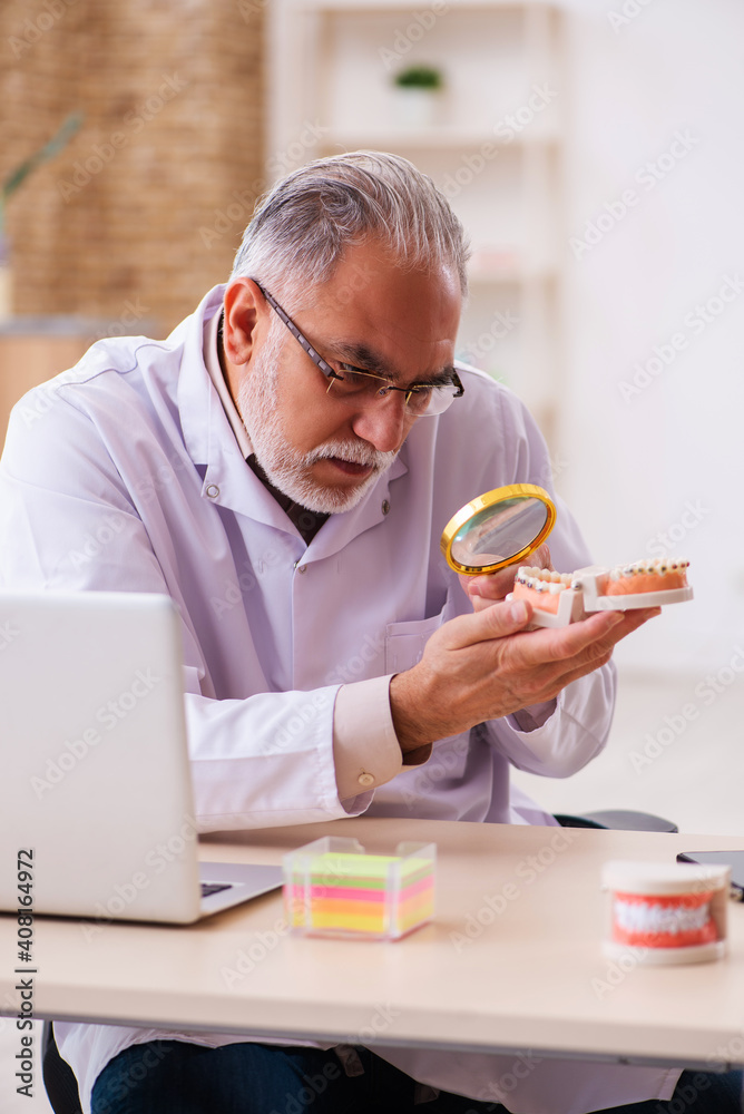Old male dentist working in the clinic Old male dentist working in the clinic