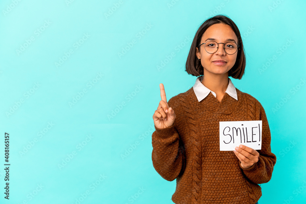 Young hispanic mixed race woman holding a smile note showing number one with finger. Young hispanic mixed race woman holding a smile note showing number one with finger.