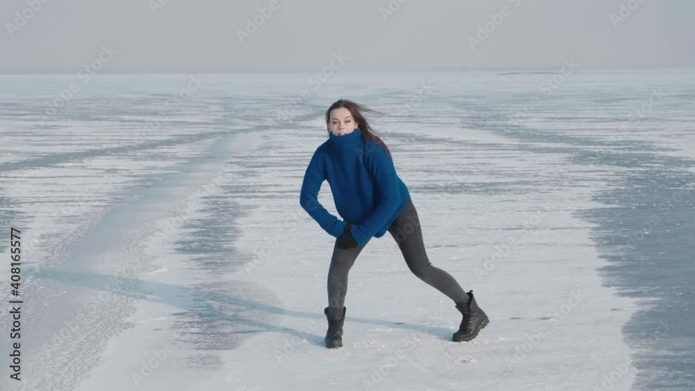 Stylish young woman in sweater, professional dancer, dancing energetic jazz funk or hip hop on frozen lake in cold winter. Female hipster dances challenge for social networks on snow-covered river Stylish young woman in sweater, professional dancer, dancing energetic jazz funk or hip hop on frozen lake in cold winter. Female hipster dances challenge for social networks on snow-covered river