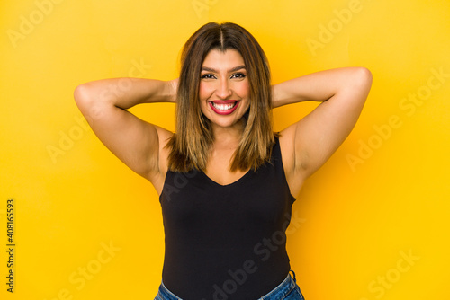 Young indian woman isolated on yellow background feeling confident, with hands behind the head.