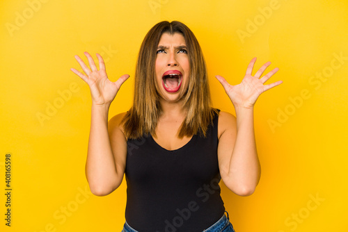 Young indian woman isolated on yellow background screaming to the sky, looking up, frustrated.