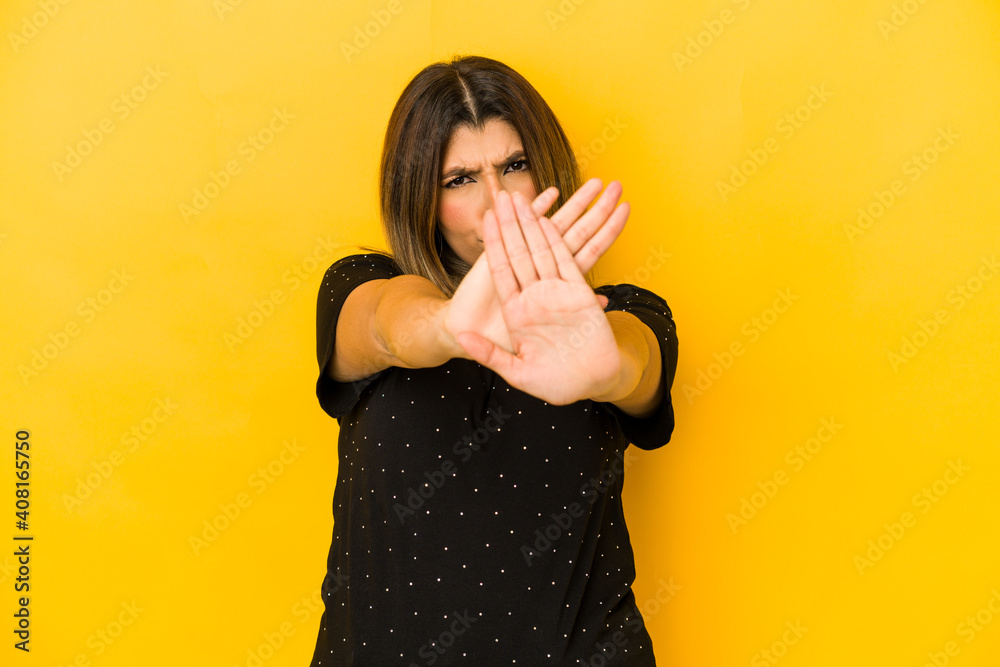 Young indian woman isolated on yellow background standing with outstretched hand showing stop sign, preventing you. Young indian woman isolated on yellow background standing with outstretched hand showing stop sign, preventing you.