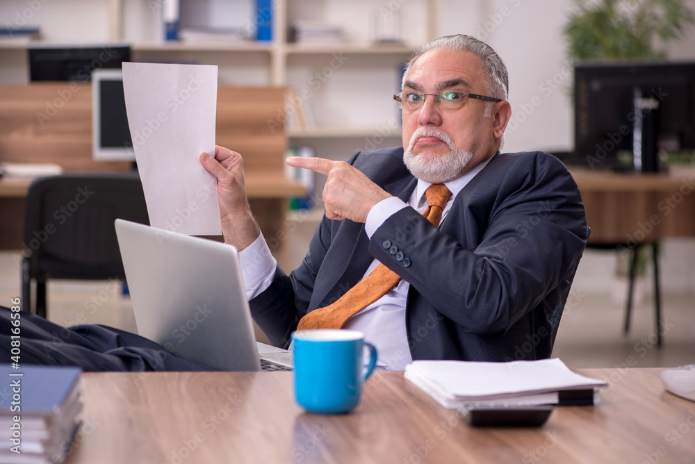 Old male employee working in the office Old male employee working in the office
