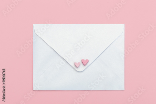 light mother-of-pearl paper craft envelope with two hearts from marshmallow isolated on pink background