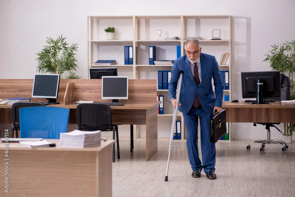 Old businessman employee after accident working in the office Old businessman employee after accident working in the office