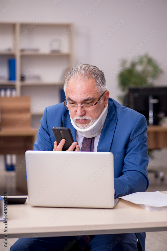 Old businessman employee after accident working in the office Old businessman employee after accident working in the office
