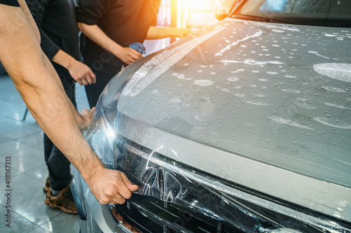 Process of installing of Paint Protection Film or PPF on new car in professional auto Detailing Center. Thin polyurethane film or polymer as protective skin from scratches and rock chips. photo