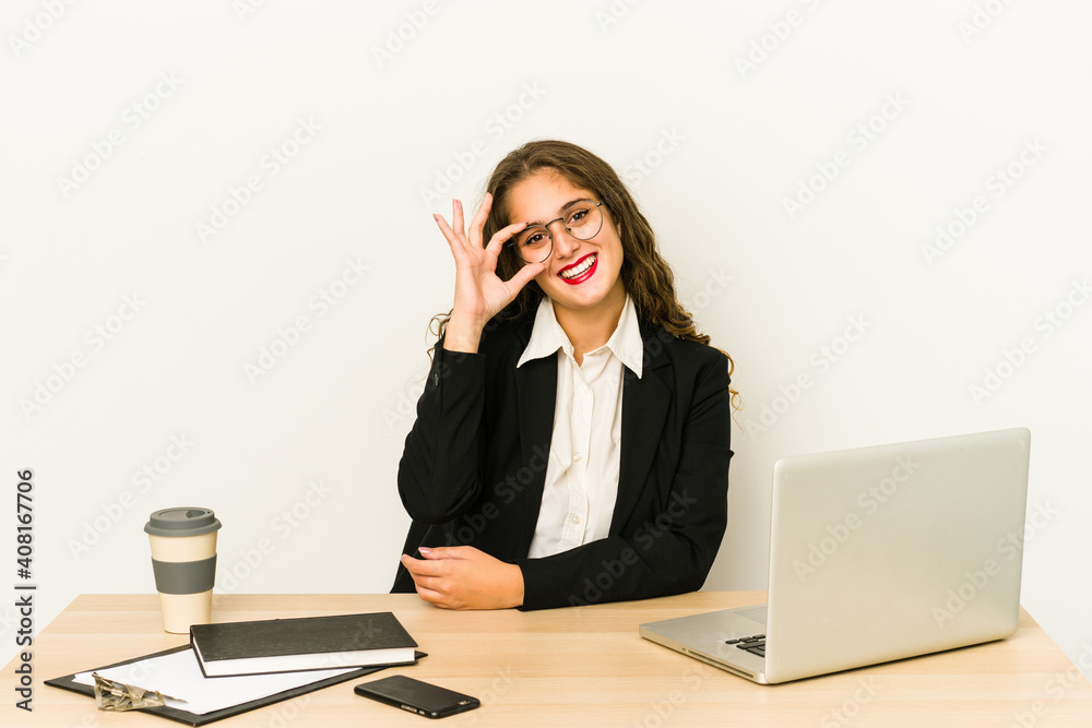Young caucasian business woman working on her desktop isolated excited keeping ok gesture on eye. Young caucasian business woman working on her desktop isolated excited keeping ok gesture on eye.