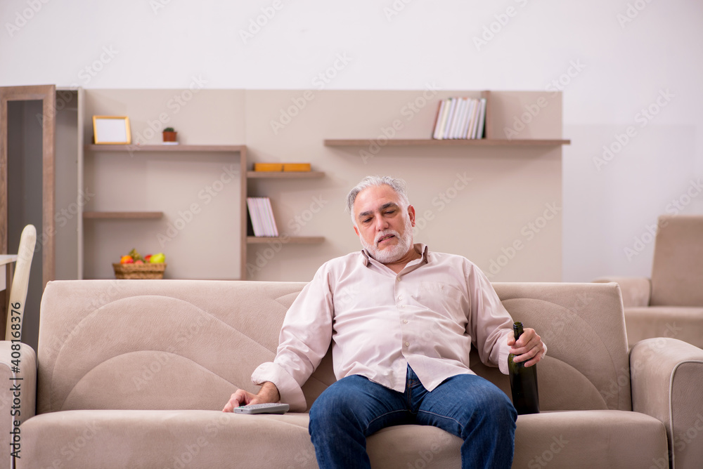 Old man drinking alcohol at home