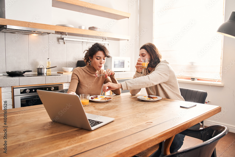 Man pricks a sausage on a fork from a plate of his wife
