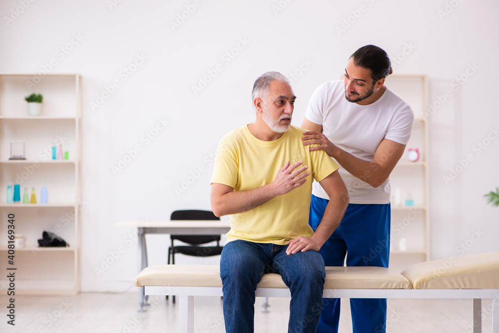Old male patient visiting young male doctor chiropractor Old male patient visiting young male doctor chiropractor
