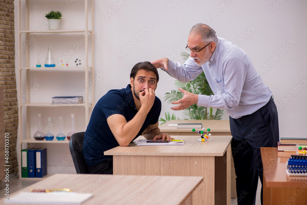 Old male teacher and young male student in the classroom Old male teacher and young male student in the classroom
