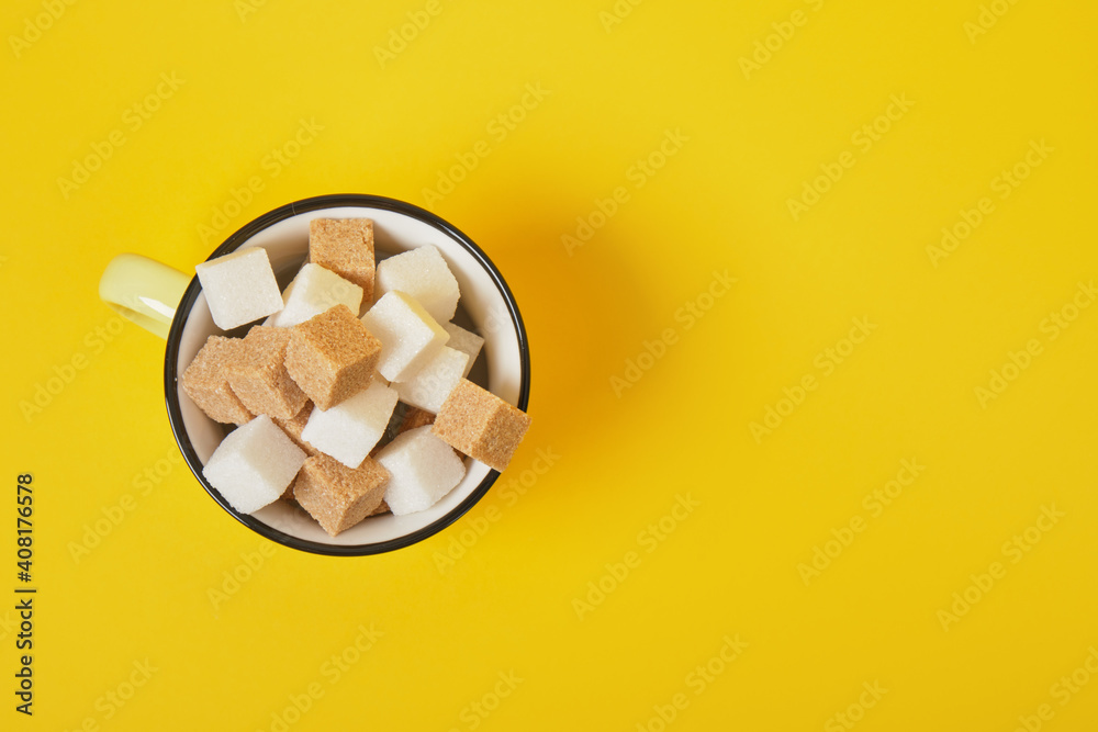 cane brown and white sugar cubes in yellow cup on yellow background cane brown and white sugar cubes in yellow cup on yellow background