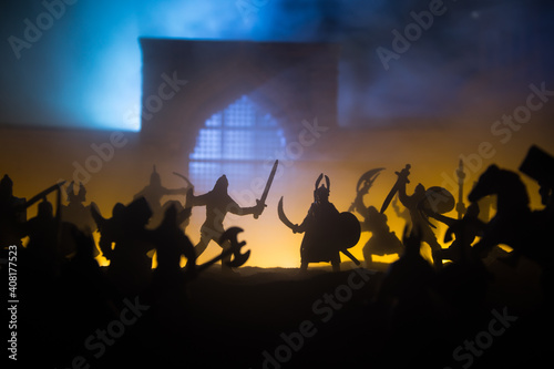 Medieval battle scene with cavalry and infantry. Silhouettes of figures as separate objects, fight between warriors on sunset foggy background.