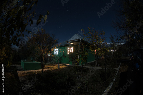 Mountain night landscape of building at forest at night with moon or vintage country house at night with clouds and stars. Summer night.