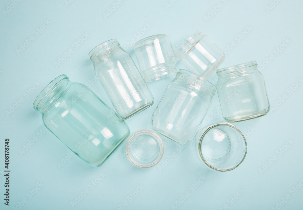 Separate collection of glass garbage. Glass cans for recycle. Eco friendly concept. Recyclable glass waste on blue: empty glass jars of different sizes. Zero waste concept. Save the planet. Go green Separate collection of glass garbage. Glass cans for recycle. Eco friendly concept. Recyclable glass waste on blue: empty glass jars of different sizes. Zero waste concept. Save the planet. Go green