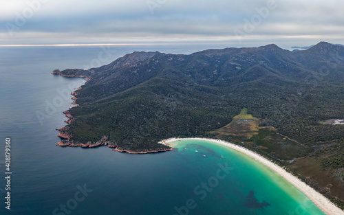 High angle panoramic aerial drone footage of Freycinet Peninsula and National Park with famous Wineglass Bay in Tasmania, Australia. Mount Graham (left) and Mount Freycinet (right) in the background. photo