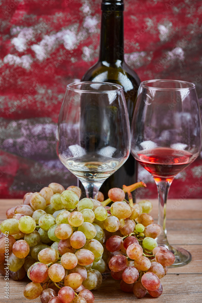 A glass of wine with green bunch of grapes