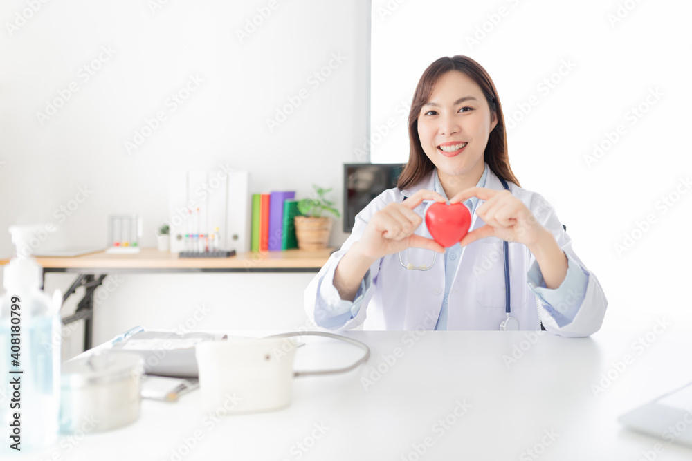 asian female doctor holding red heart model, heart health care, she feeling happy and smile in Cardiac clinic center asian female doctor holding red heart model, heart health care, she feeling happy and smile in Cardiac clinic center