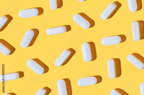 Modern pattern with hard shadows of white pills on yellow background. Food supplement, multivitamins, medications