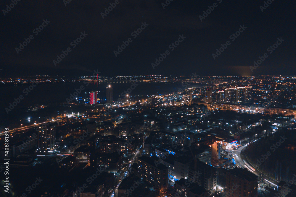 Drone view at night, with illuminated streets and dark sky. Beautiful cityscape