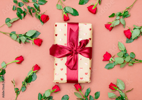 Bouquet of red roses and gift box on pink background
