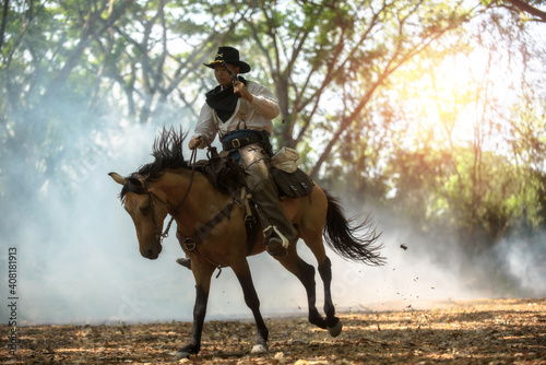 Fotografie, Obraz Cowboy riding a horse carrying a gun