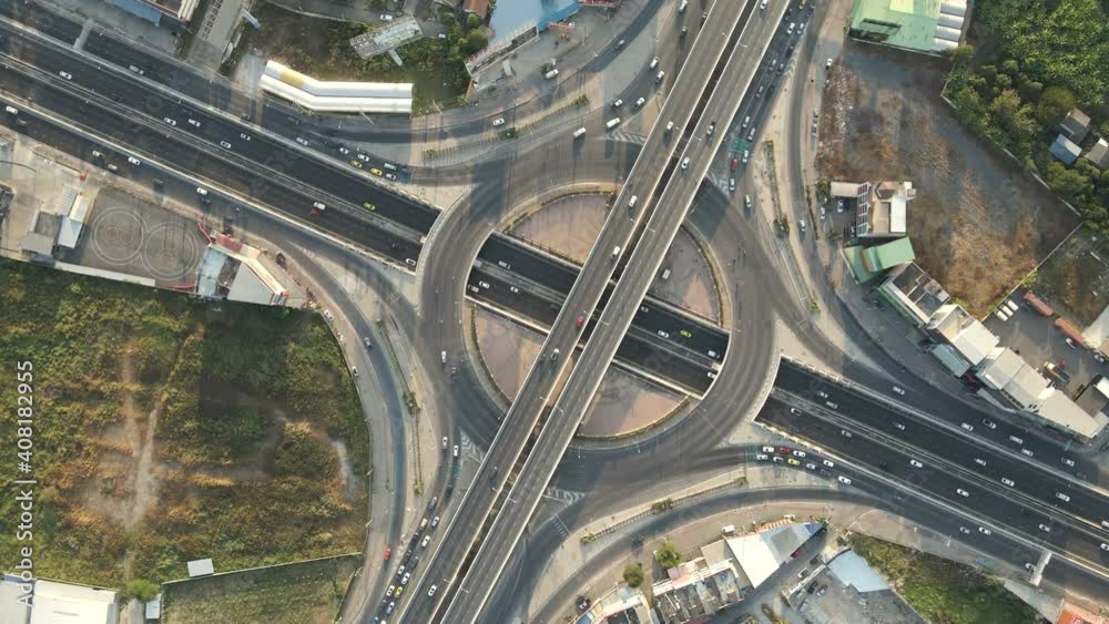 Fast rotated top-down angle aerial drone shot of roundabout and crossing expressway with evening busy traffic. Fast rotated top-down angle aerial drone shot of roundabout and crossing expressway with evening busy traffic.