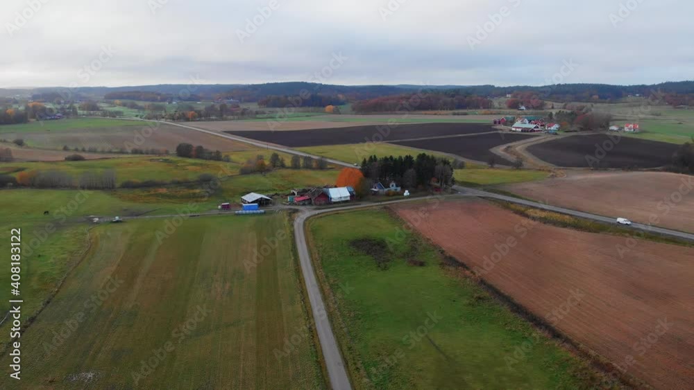 Bird's aerial drone view of countryside agriculture field landscape on overcast cloudy day, Sweden, lowering