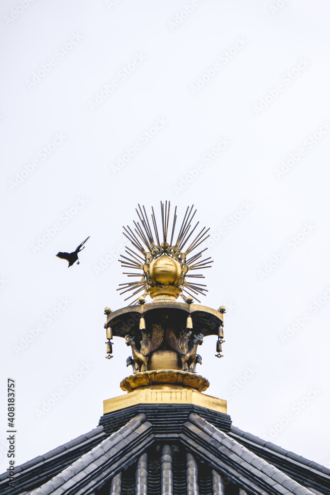 Obraz premium Detail of the golden roof decoration of a buddhist temple wit a crow flying