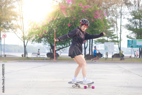 Asian women on skates board outdoors on beautiful summer day. Happy young women play surfskate at park on morning time. Sport activity lifestyle concept