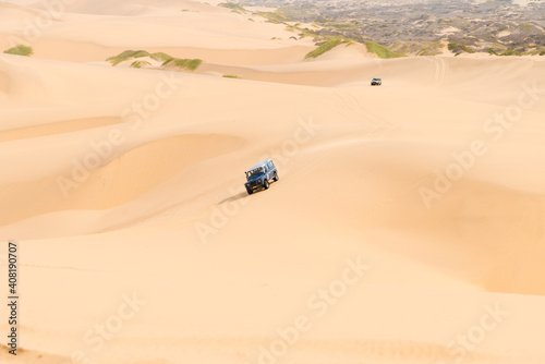 A Car Drives Down A Large Namib Dune On The Atlantic Ocean, Sandwich Harbor, Erongo, Namibia © Stockfotos