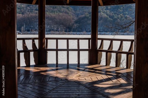 View inside covered pavilion beside frozen lake. © aminkorea