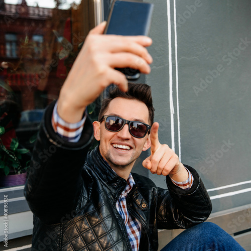 a man of European appearance in sunglasses. A man makes a video call or takes a selfie, close-up portrait. point your finger.