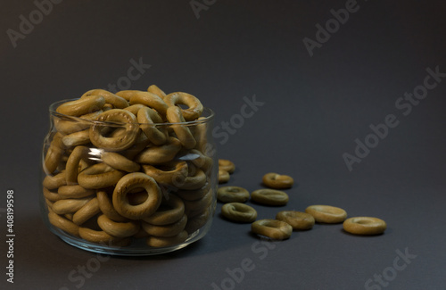 Yellow small sushki bagels in glassware on a black background. Bagels are scattered around it. photo