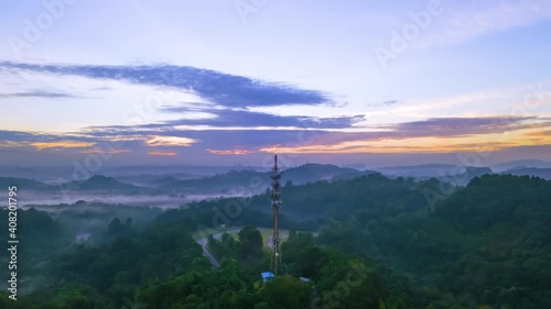 Cinematic hyperlapse Aerial footage circle view of 5G Communication tower during morning sunrise with clouds, mists and fog