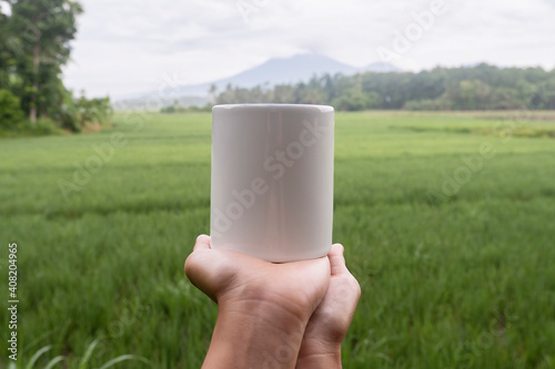 mug mockup. White mug with a background of raung mountains and the rice fields of Banyuwangi Regency photo