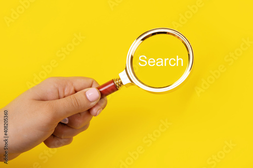 magnifier in hand with inscription search over yellow background, search concept