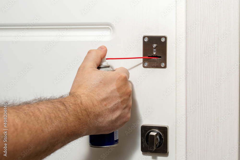 a man fixing a door lock with a lubricant a man fixing a door lock with a lubricant