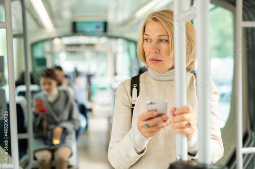 Portrait of female passenger using mobile phone in tram. High quality photo