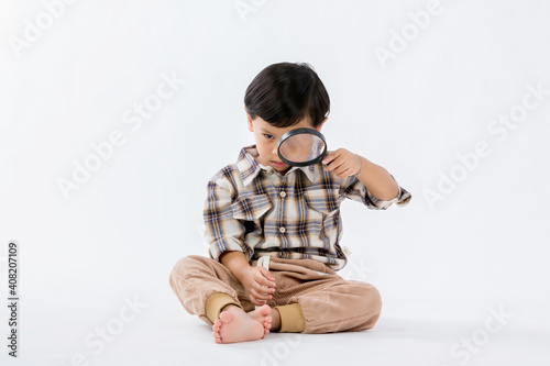 Wallpaper Mural Child holding magnifying glass on white background. Boy with a magnifying glass in studio. Positive curious boy in casual wear looking at through magnifier  Torontodigital.ca